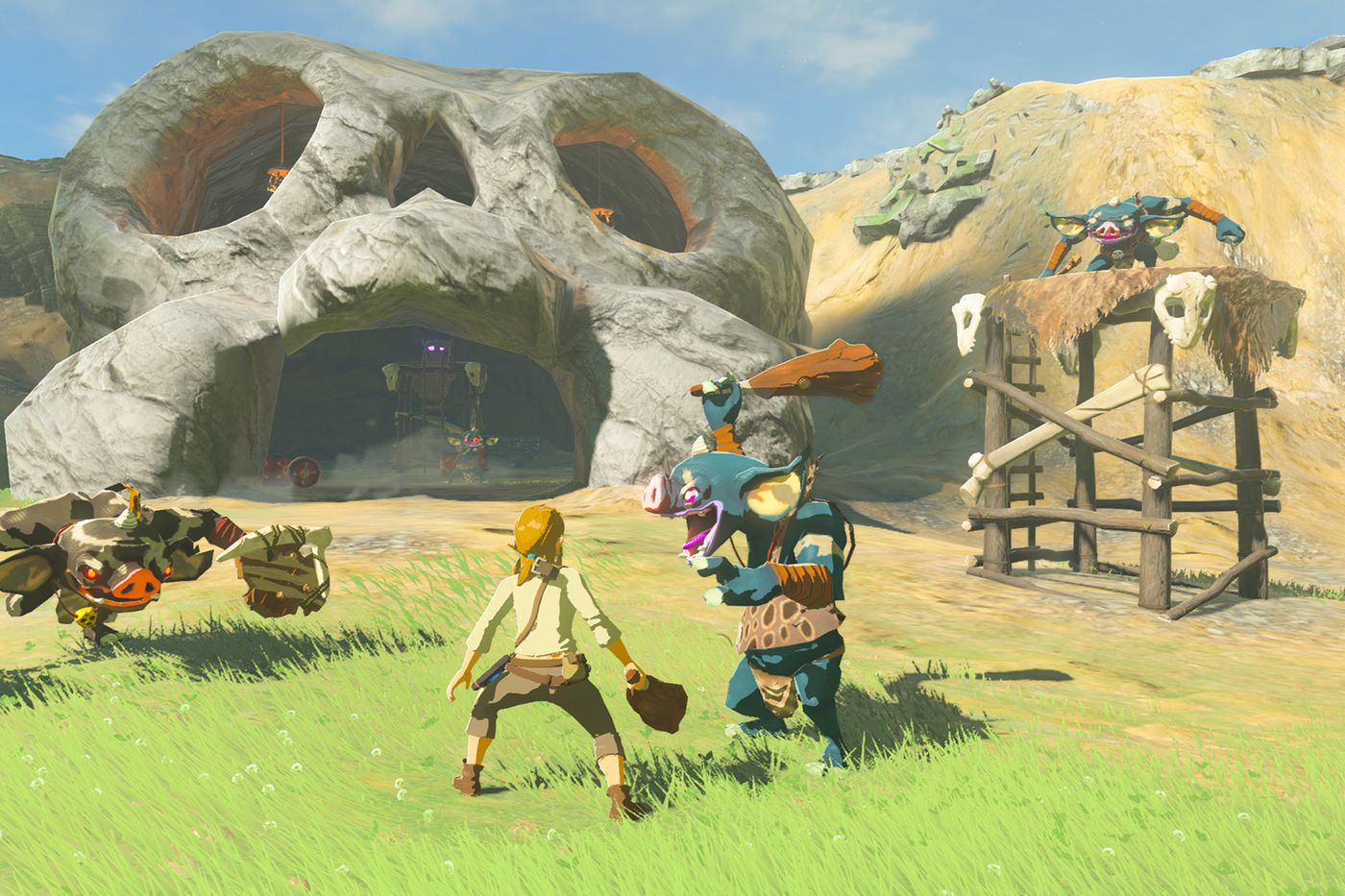 Link from the Legend of Zelda: Breath of the Wild facing enemy bokoblins in front of a large skull cave